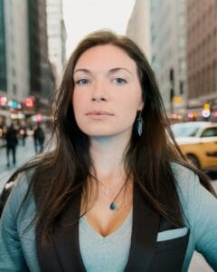 A woman standing in the street with her eyes closed.