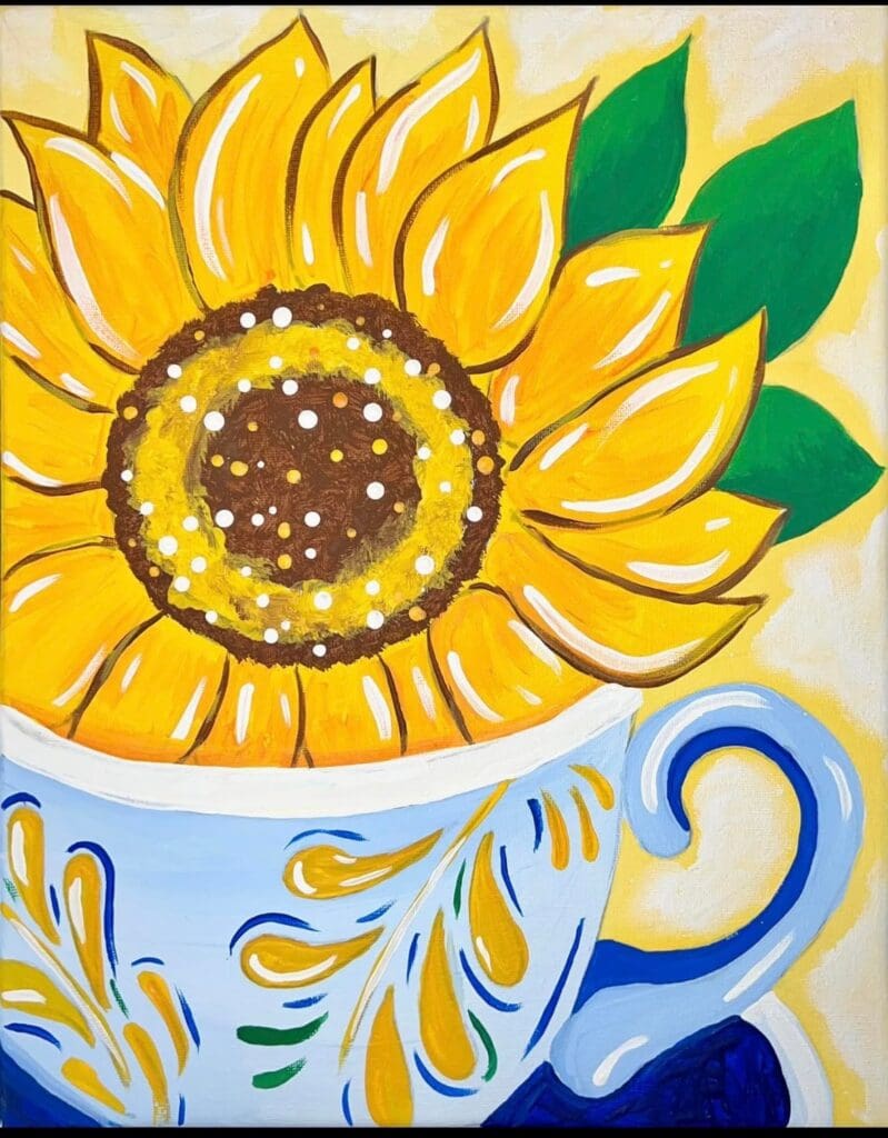 A colorful teacup filled with a large sunflower.